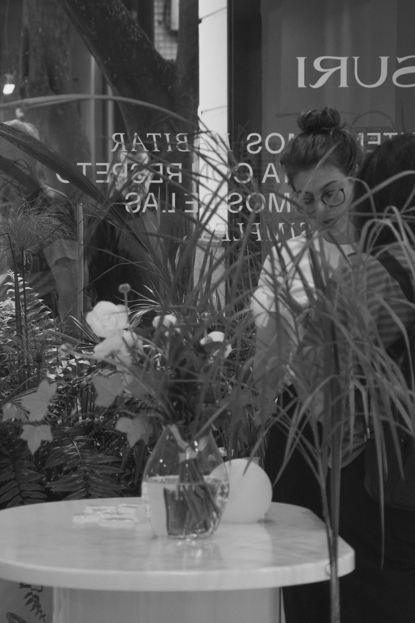 Suri storefront reflection — flowers, plants, B&W