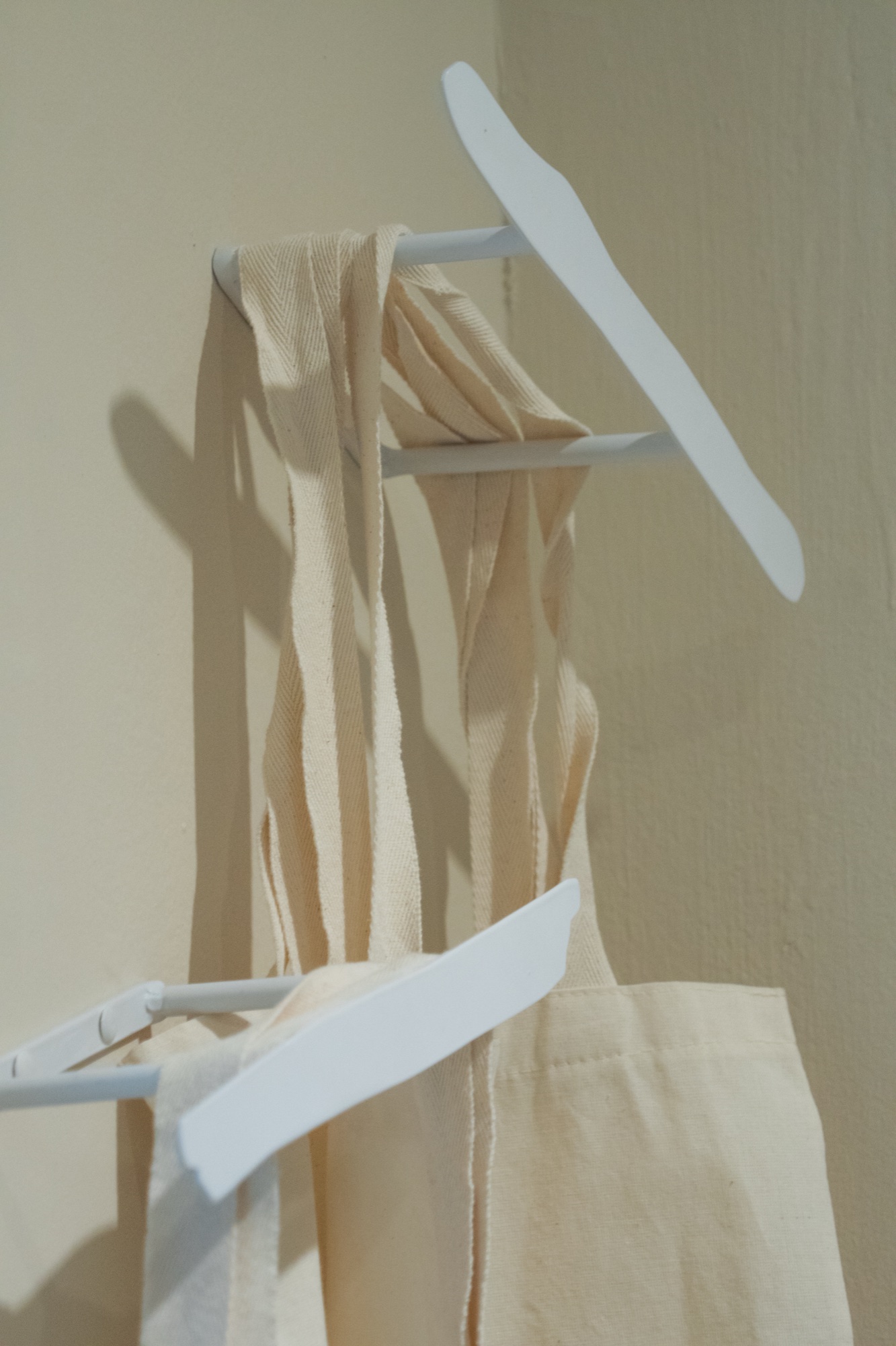 Tote bags hanging — cream cotton, studio shot