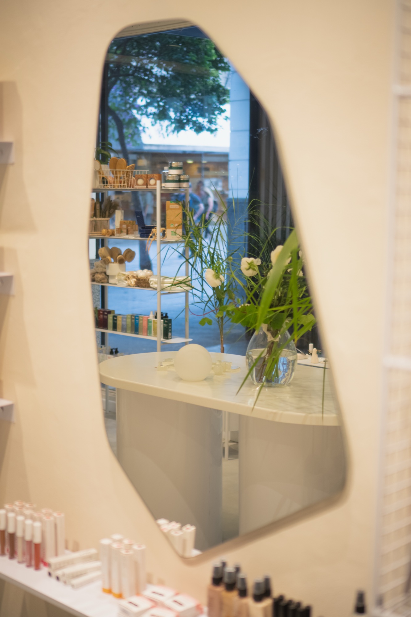 Organic-shape mirror on the wall, products on display