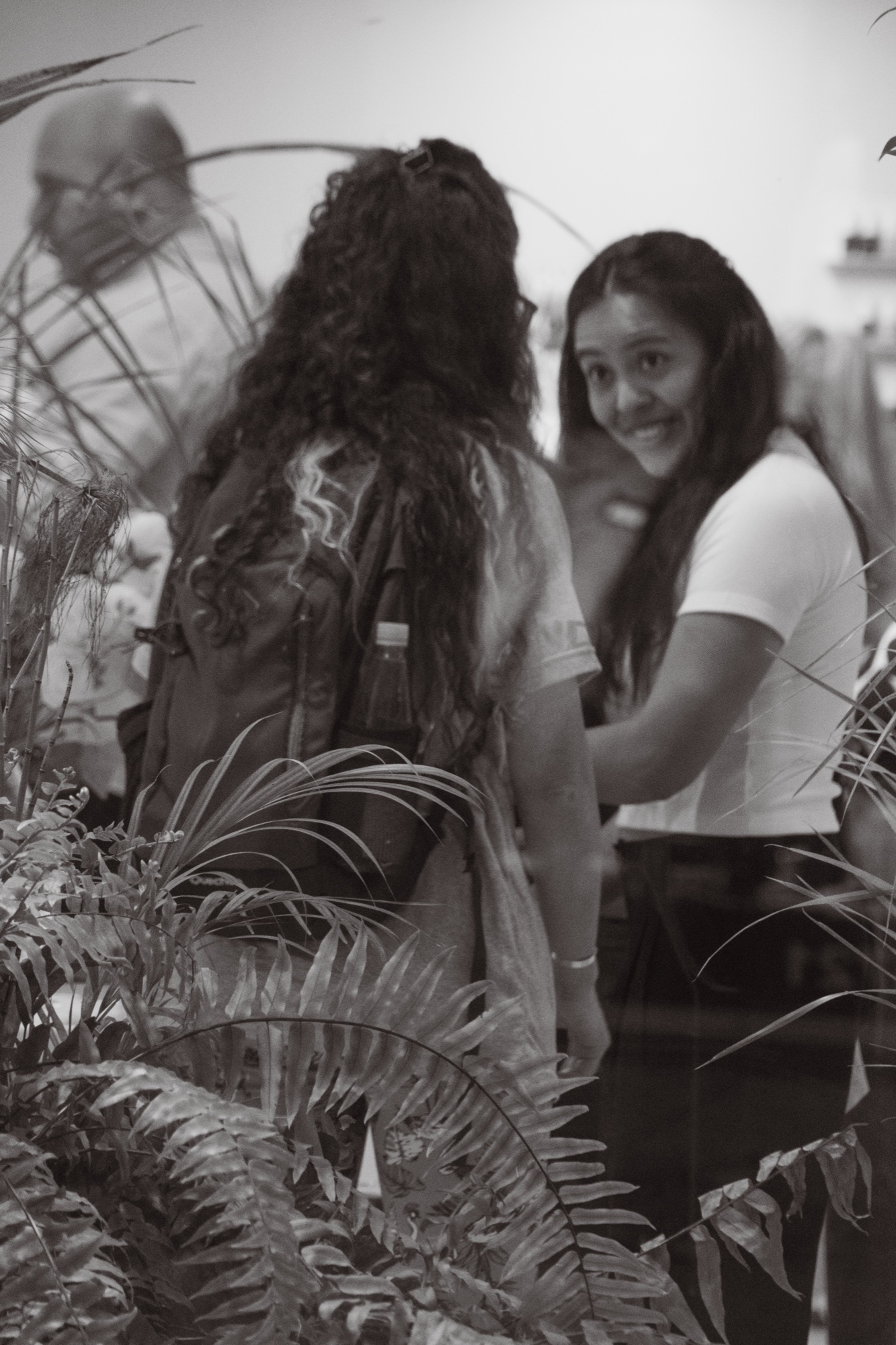 Two women talking inside the store, plants in foreground